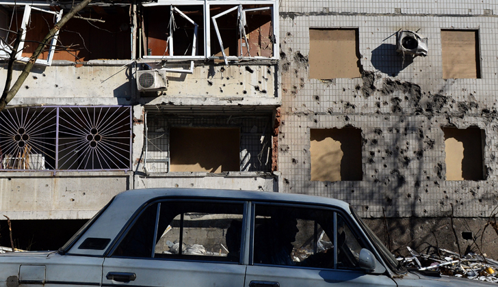 Un hombre conduce su auto frente a un edificio bombardeado en Donetsk, Ucrania. Rusia, Francia, Alemania y Ucrania han acordado el retiro de armamentos de las fronteras de Ucrania y el cese al fuego. / Foto: Vasily Maximov - AFP