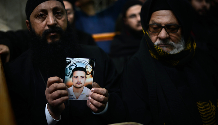 Un clérigo copto sostiene una imagen de unas de las personas decapitadas por el estado islámico, en Libia. / Foto: Mohamed El-Shamed - AFP