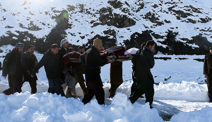 Varios hombres afganos llevan el cuerpo de uno de los fallecidos en los recientes alúdes de nieve en la ciudad de Khench. / Foto: Shah Marai - AFP