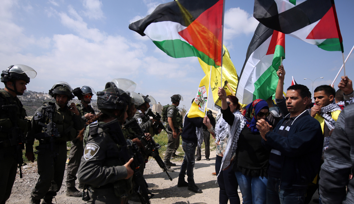 Un grupo de manifestantes palestinos ondean sus banderas de forma pacífica frente a oficiales de las fuerzas de seguridad israelíes en una manifestación para hacerse escuchar, tras los constantes avances de los asentamientos de Israel en territorio palestino.
