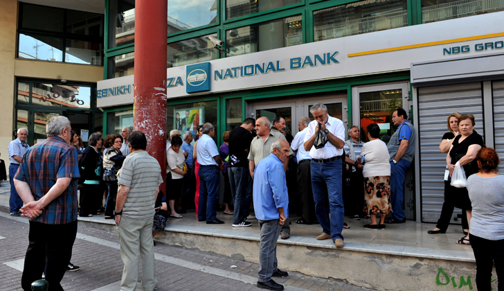 Usuarios de uno de los bancos griegos hacen fila a las afueras de los cajeros automáticos, para lograr retirar los únicos 60 euros diarios que se puede extraer de las cuentas bancarias. Foto: Sakis Mitrolidis - AFP.