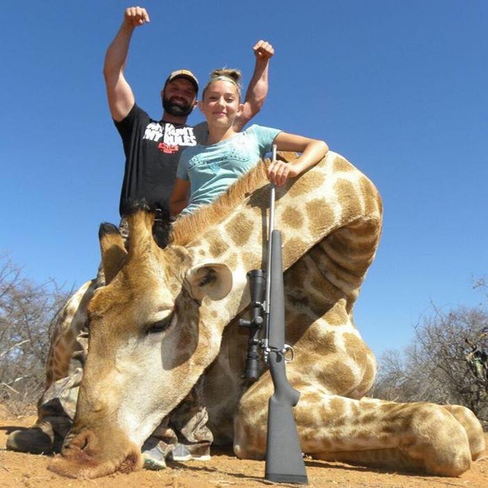 La niña posa junto a su padre detrás de una jirafa muerta a disparos en Sudáfrica. Foto: Aryanna Gourdin - Braids and Bows. 