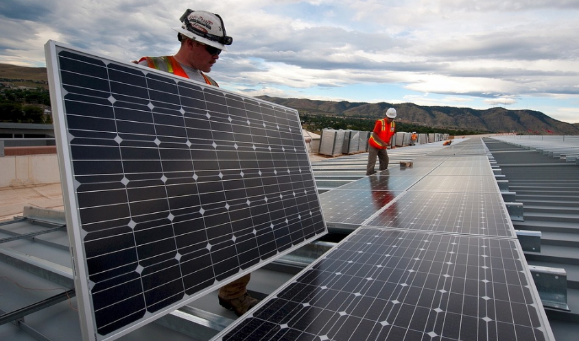 Dos técnicos colocan paneles solares en el techo de un complejo industrial. Foto: Pixabay.
