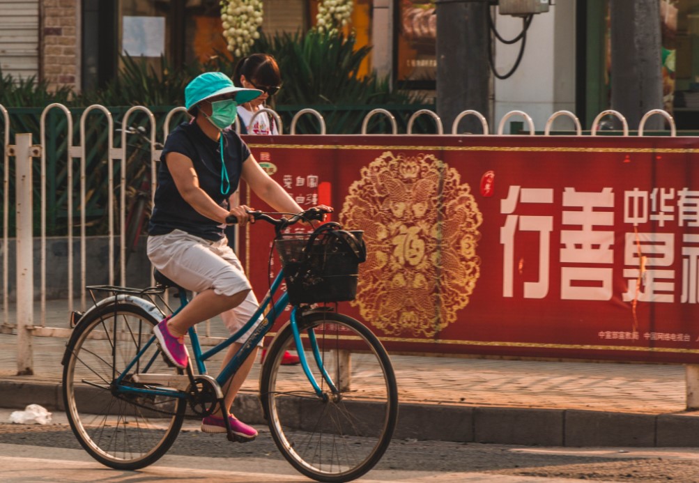 Una mujer transita en bicicleta por Beijing mientras usa un barbijo para evitar inhalar smog. Foto: Pixabay