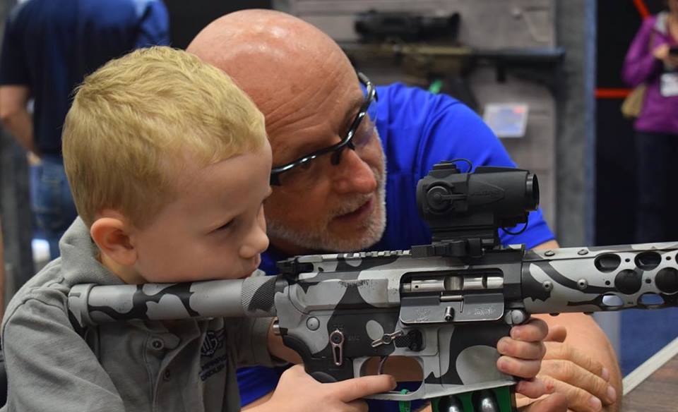 Un experto en armas enseña a un niño pequeño a disparar un rifle de asalto en una convención de la NRA en Dallas, Texas. Foto: NRA / Facebook