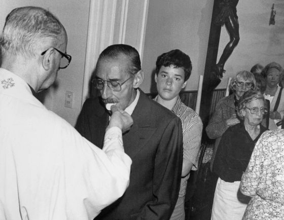 En esta fotografía de archivo se ve cómo el dictador Jorge Videla recibe la comunión de un sacerdote local