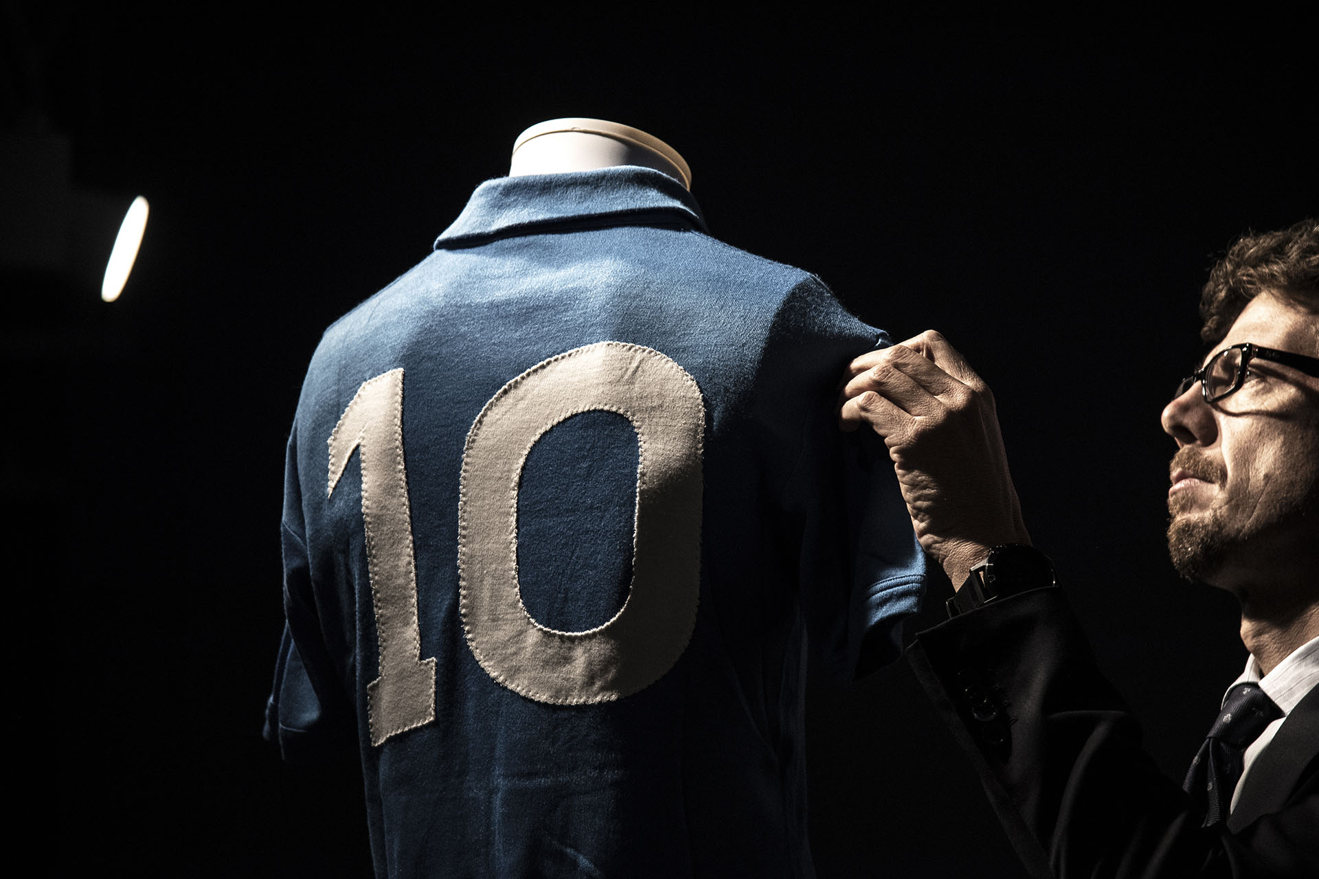 A man displays a S.S.C. Napoli football jersey worn by Argentina's football legend Diego Armando Maradona during the 1986-1987 season, from the collection "Football Memorabilia" at the Aste Bolaffi auction house in Turin on December 4, 2018. (Photo by MARCO BERTORELLO / AFP)