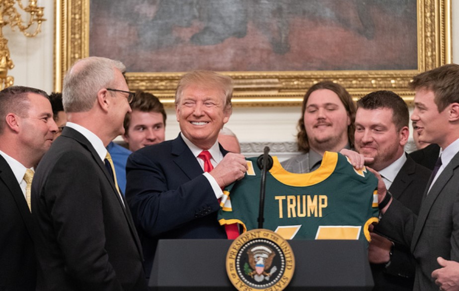 Trump sostiene una camiseta de un equipo de fútbol americano con su nombre. Foto: The White House
