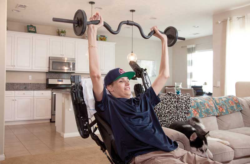 Kris Boesen sostiene unas pesas, algo que hace meses, cuando estaba cuadripléjico, no era posible. Foto: Greg Iger