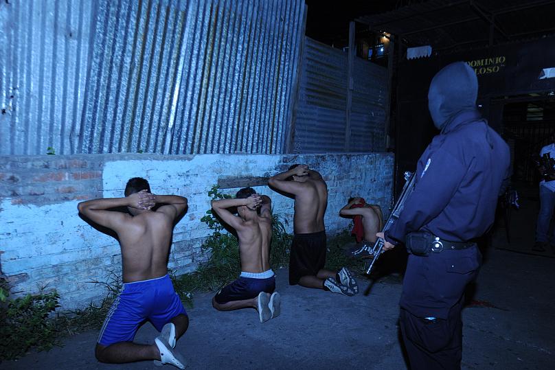 Un policía vigila a cuatro miembros de una mara. Foto cortesía de El Nuevo Diario de El Salvador / Mary Cortez
