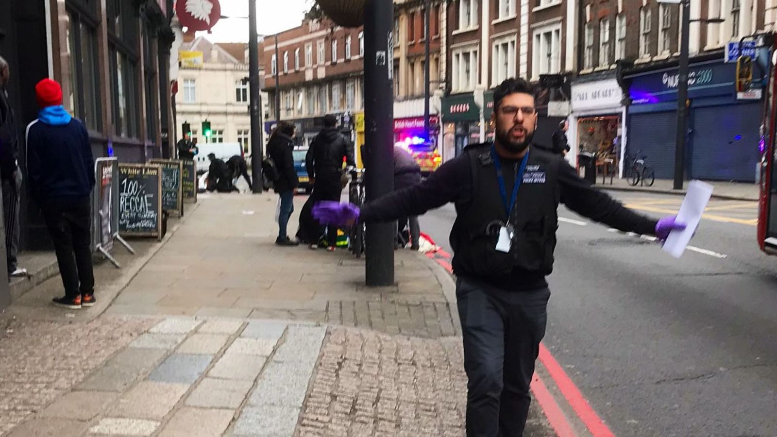 Un policía aleja a los transeúntes y la prensa del área del ataque ocurrido este domingo en el sur de Londres. 