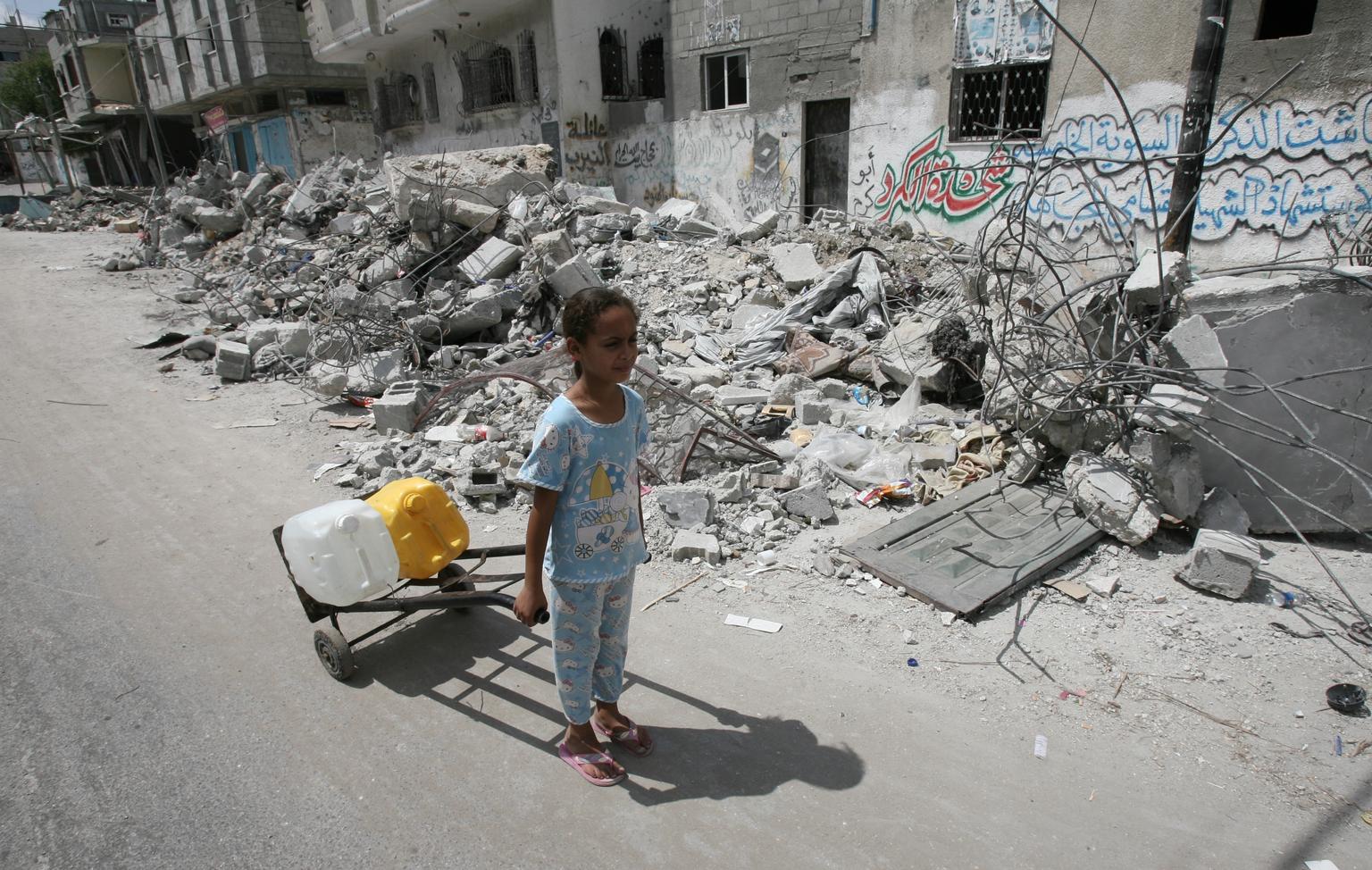 Una niña transporta agua en medio de una zona de Gaza destruida por bombardeos de Israel. Foto: UNICEF