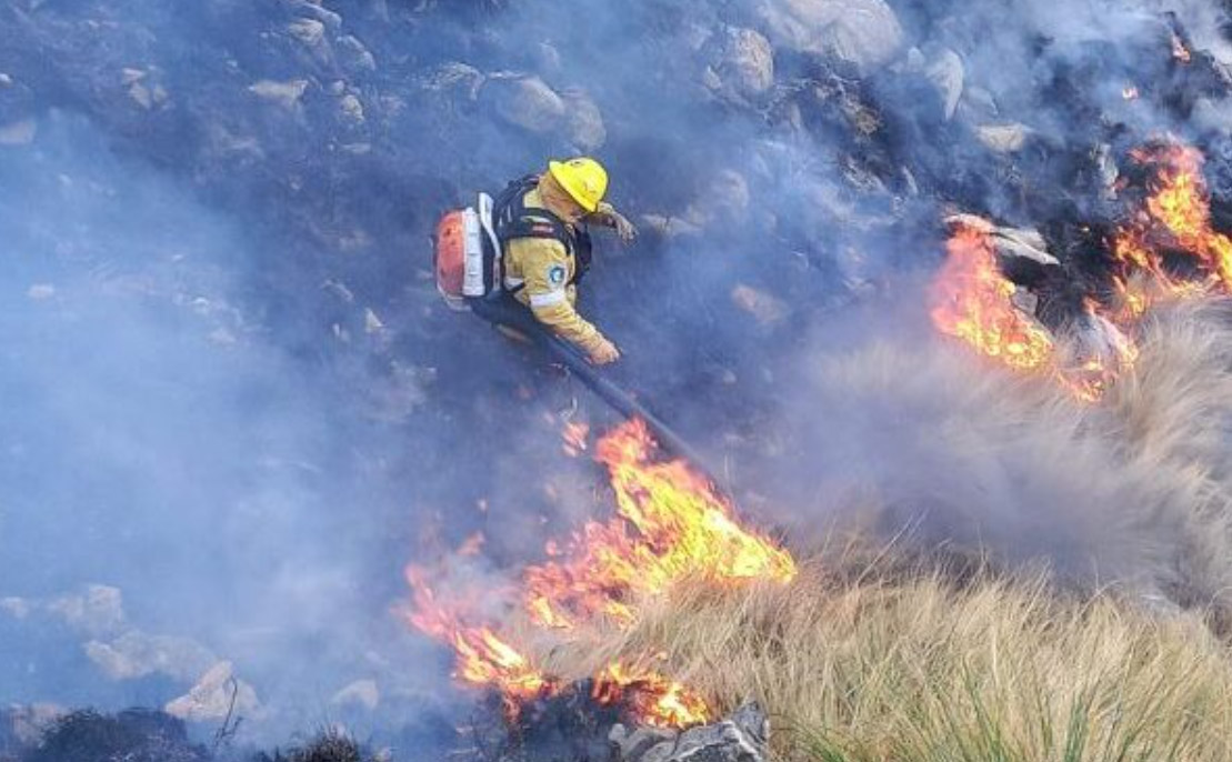 Bombero lucha contra el fuego entre la tierra devastada.