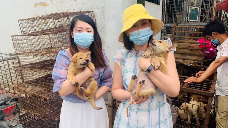 Dos activistas de Humane Society sostienen dos cachorros rescatados del mercado de Yulin. Foto: Humane Society Internacional