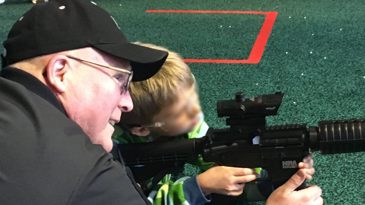 Un hombre muestra un rifle de asalto a un niño pequeño (el rostro del menor ha sido difuminado para preservar su identidad), en un evento de la Asociación Nacional del Rifle de EE.UU. Foto de archivo: Facebook / NRA