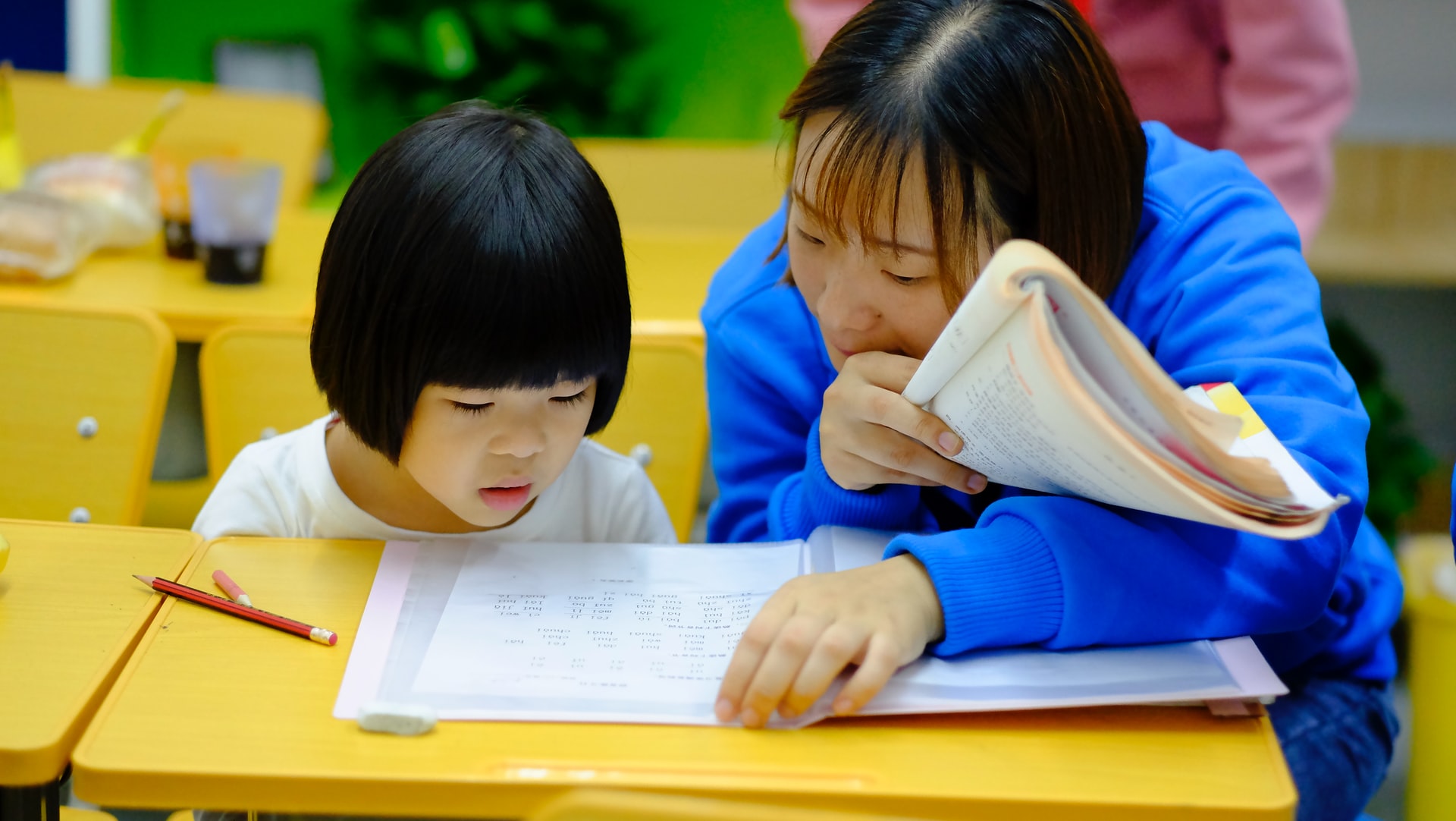 Una maestra habla con una niña en una escuela en China. Foto: UNsplash / Jerry Wang