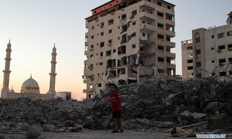 Un niño palestino se encuentra cerca de los escombros de un edificio destruido por los ataques aéreos israelíes en la ciudad de Gaza, el 21 de junio de 2021. Foto cortesía de Xinhua