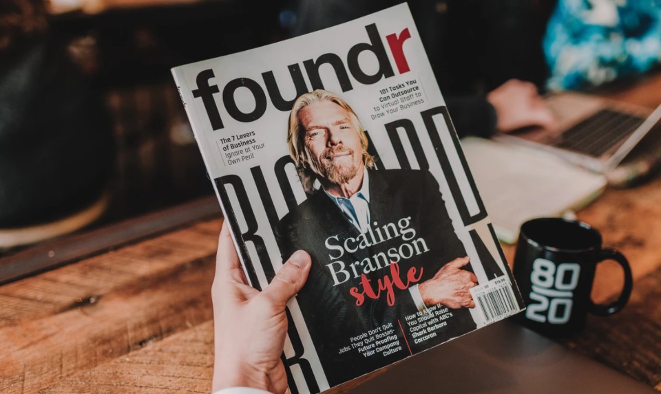 Una persona sostiene una revista con la foto de Richard Branson, multimillonario inglés con una fortuna de 4.900 millones de dólares. Foto: Unsplash / Austin Distel