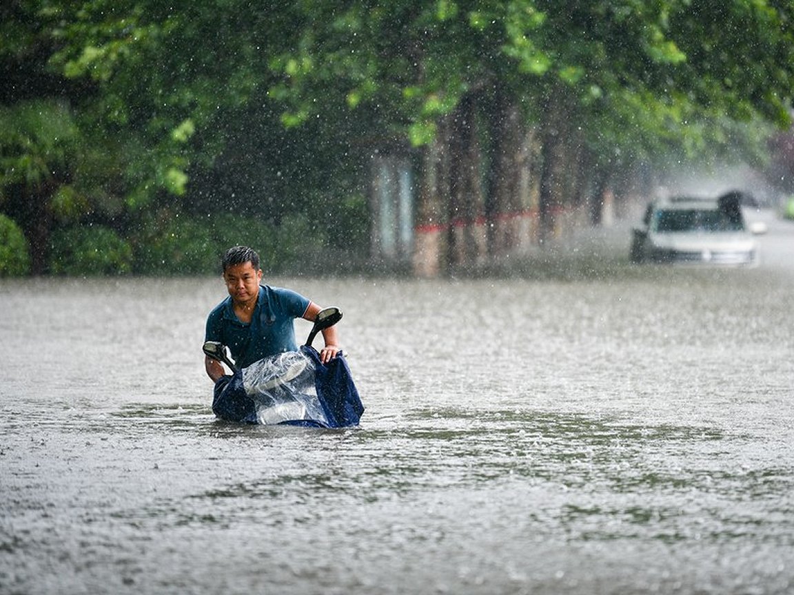 Un hombre afectados por las inundaciones camina con su moto, casi cubierta por el agua. Foto: Cruz Roja y Media Luna Roja Internacional