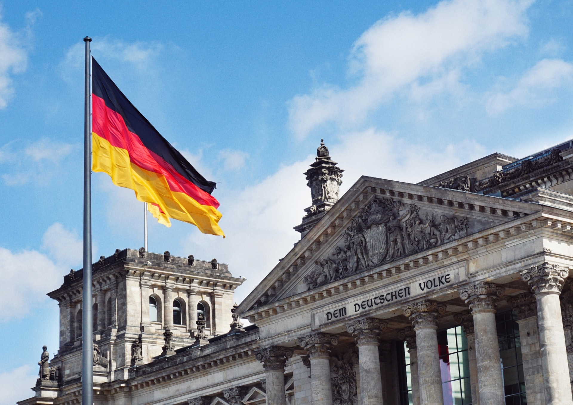 La bandera alemana ondea frente al Parlamento alemán en Berlín. Foto: UNsplash / Maheshkumar Painam