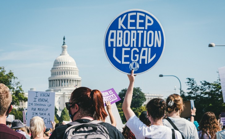 Una manifestante sostiene una pancarta que dice "Mantener el aborto legal" frente al Capitolio de Washington. Foto: UNsplash / Gayatri Malhotra