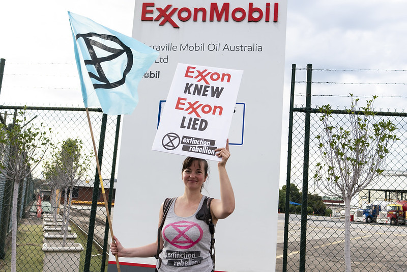 Una mujer sostiene un cartel que dice “Exxon sabía, Exxon mintió” en una protesta contra Exxonmobil en Australia en 2022. Foto: Flickr / Matt Hrkac