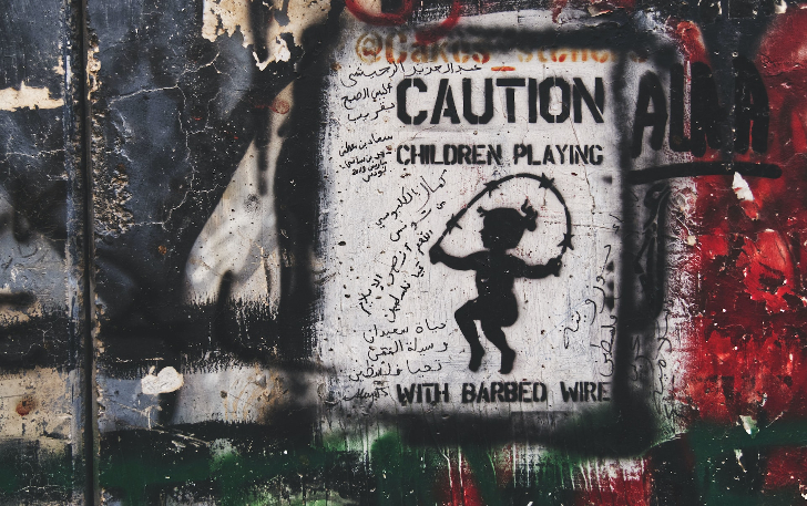 "Cuidado: Niños jugando con alambre de púas", dice un grafitti pintado en la pared construida por Israel para encerrar a los territorios palestinos. Foto: Jakob Rubner