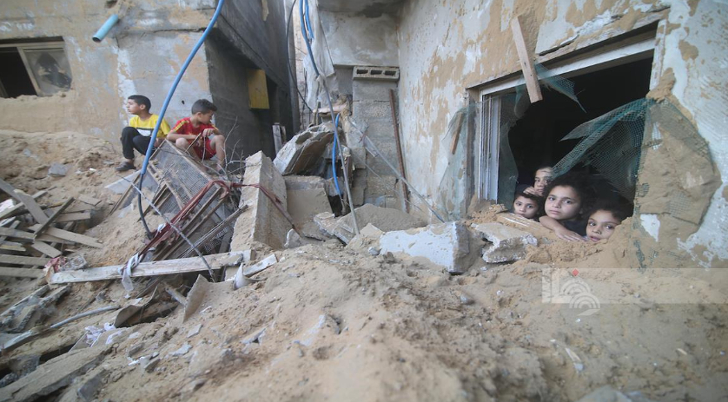 Niños se asoman por las ventanas de lo que fue su hogar, ahora destruido por los bombardeos israelíes. Foto cortesía de la agencia palestina Wafa