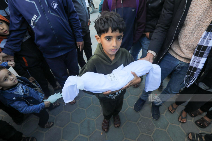 Un niño sostiene el cuerpo de su pequeño hermano, asesinado por el ejército israelí en un bombardeo esta semana. Foto: Agencia de noticias palestina Wafa