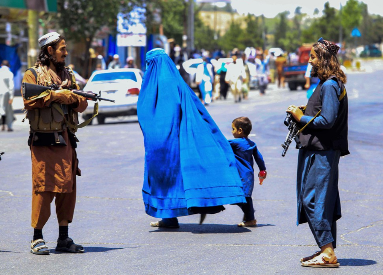Mucho peor que "El cuento de la criada", una mujer cruza la calle completamente tapada de pies a cabeza con su hijo, ambos vistiendo de color azul como uniforme, rodeada de hombres armados.