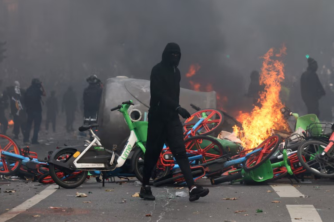 Imagen de redes sociales, un montón de bicicletas de uso público amontonadas en llamas. arden de trás de un manifestante violento que se aleja caminando.